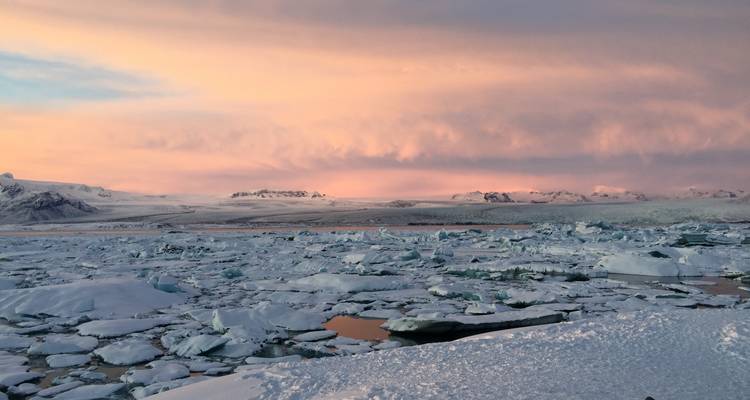Paysage gelé avec des icebergs sous un ciel coloré.