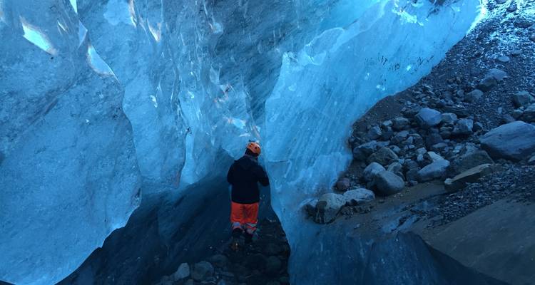Personne explorant une grotte de glace bleue.