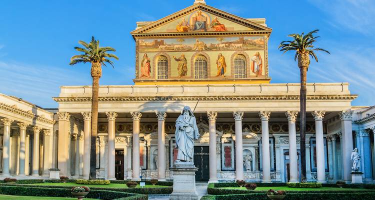Majestätische Basilika-Fassade mit leuchtenden Mosaiken und Palmen vor einem Säulenhof zur goldenen Stunde.