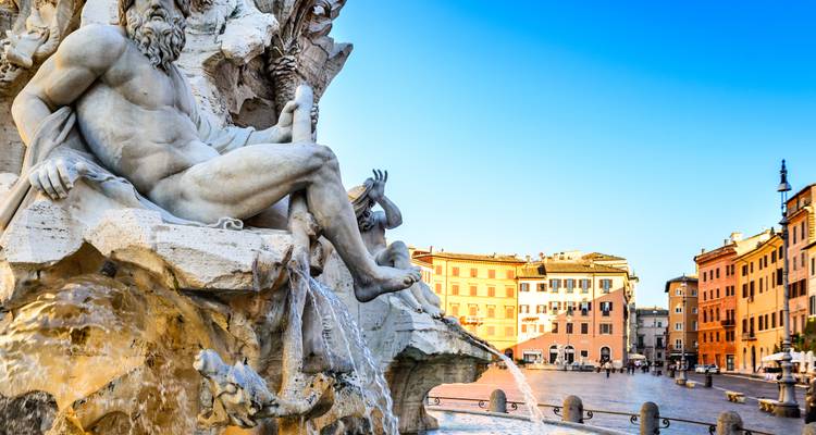 Nahaufnahme von Berninis Vierströmebrunnen mit funkelndem Wasser vor bunten römischen Gebäuden.