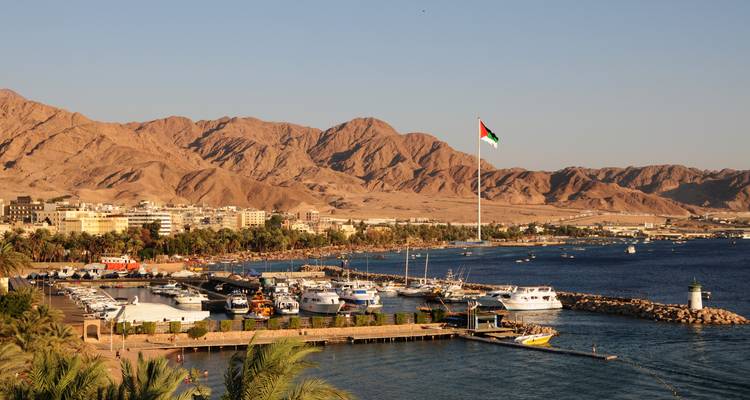 Aqaba-Marina mit Jordaniens riesigem Fahnenmast, Booten und kargen Bergen unter der Nachmittagssonne.