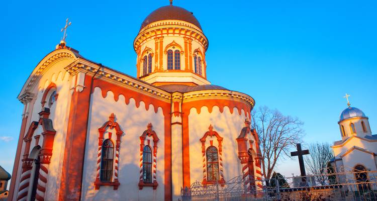 Lumière chaude du soir sur une église orthodoxe ornée avec une façade rayée rouge et blanche.