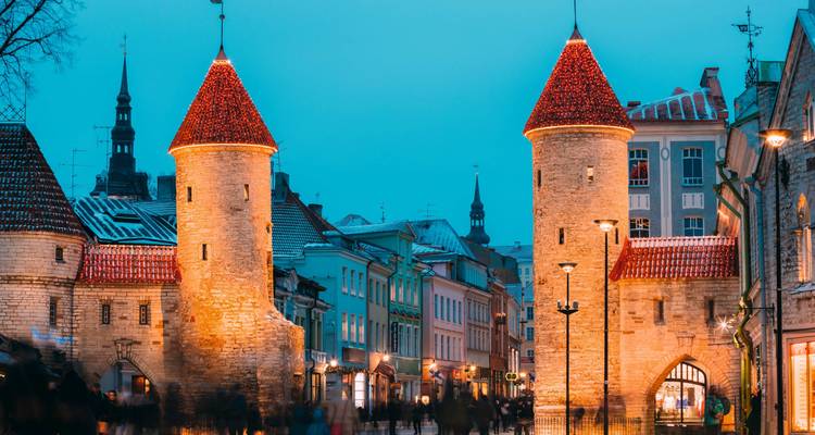Historisches Stadttor und umliegende Gebäude am Abend beleuchtet.