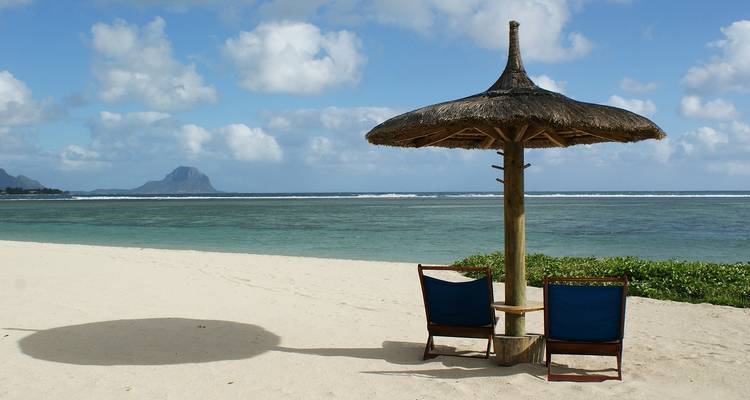 Plage avec parasols et montagne en arrière-plan.
