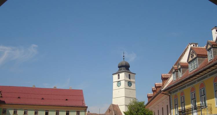 Zicht op een historische klokkentoren en kleurrijke gebouwen onder een heldere blauwe hemel.