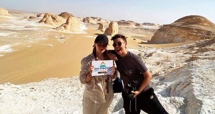 Two people holding a sign in the desert landscape.