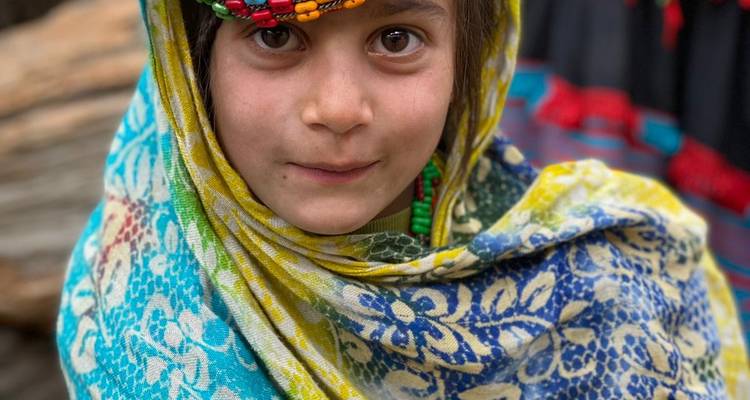 Porträt eines jungen Mädchens in farbenfroher traditioneller Kleidung mit einem Kopfschmuck aus Perlen.