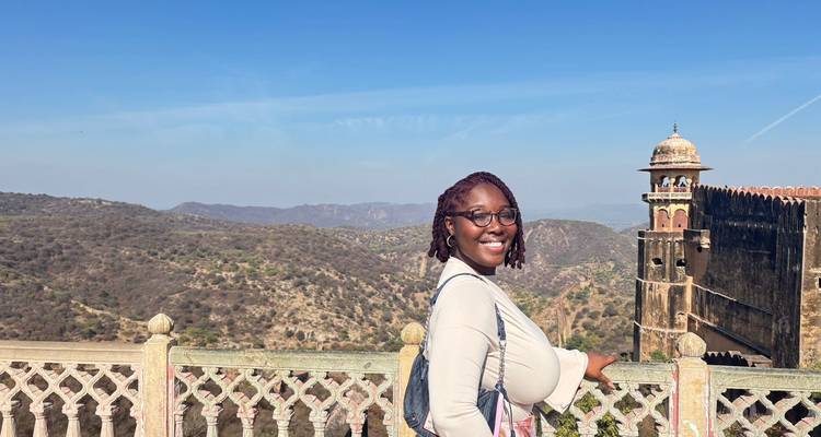 Frau lächelt mit Blick auf eine Festung und Landschaft.