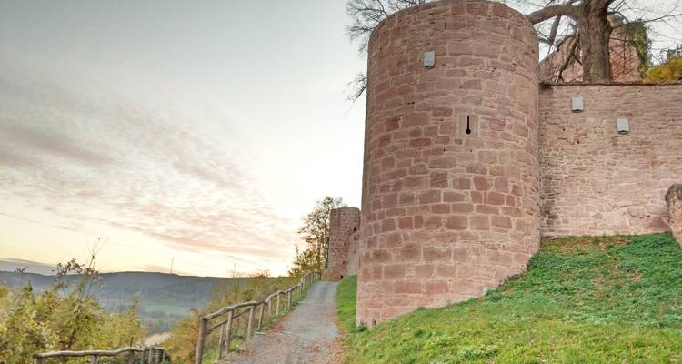 Stone defensive towers and walls line a hillside footpath at dusk.