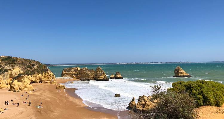 Goldener Sandstrand mit dramatischen Felstürmen und türkisfarbenen Atlantikwellen entlang der Algarve-Küste