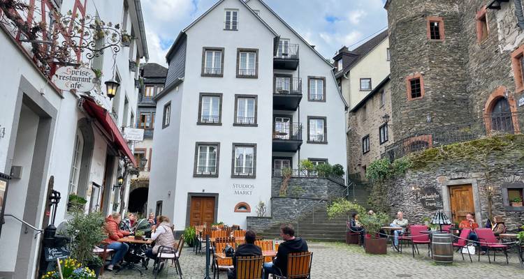 Buitencafé op een geplaveide binnenplaats waar locals en toeristen dineren tussen historische stenen gebouwen.