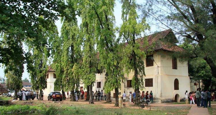 Oud koloniaal gebouw met mensen die eromheen verzameld zijn.