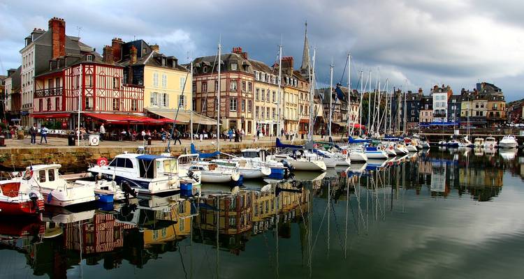 Port coloré avec des bateaux et des bâtiments traditionnels se reflétant dans l'eau.