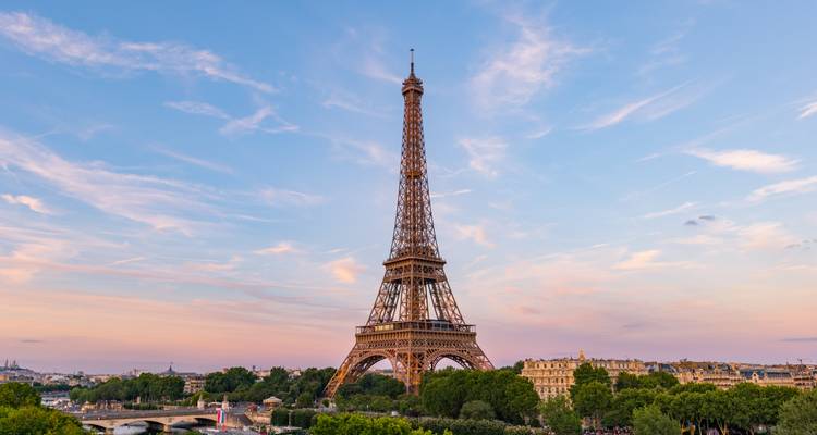 Tour Eiffel emblématique sous un ciel dégagé, entourée de verdure et d'un paysage urbain.