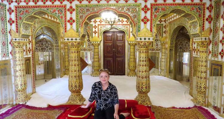 Frau sitzt in einem reich verzierten Raum.