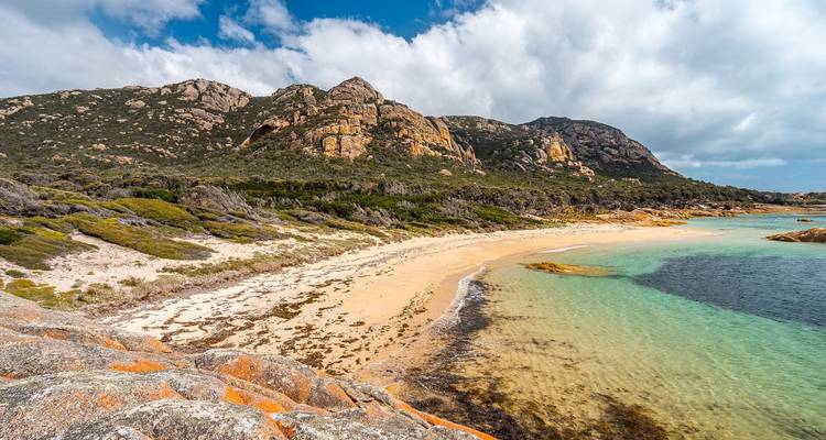 A coastal landscape with a sandy beach and turquoise waters.