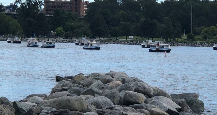 De nombreuses petites embarcations sur une rivière avec des arbres le long des rives.