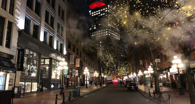 Vue nocturne d'une rue de ville avec des éclairages décoratifs et de la vapeur.
