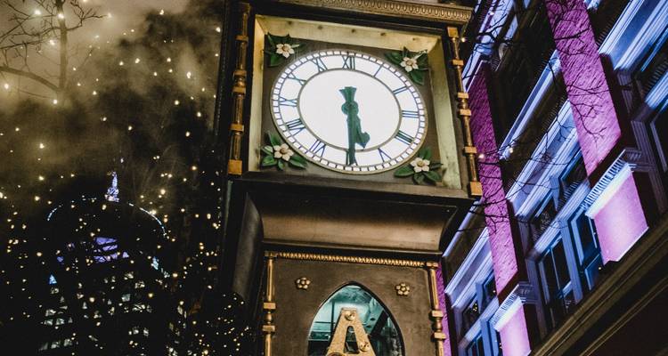 Tour d'horloge ornée entourée de lumières festives la nuit.