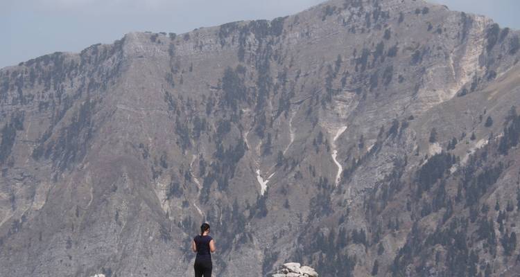 A person standing on a rocky terrain with a vast mountainous background.