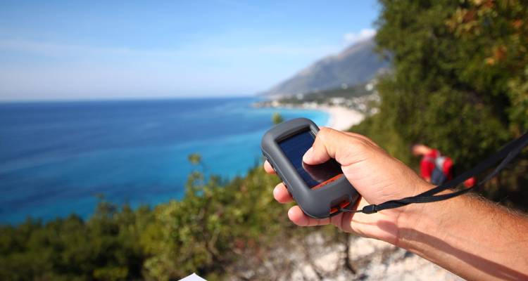 A person holding a device looking over the coastline.