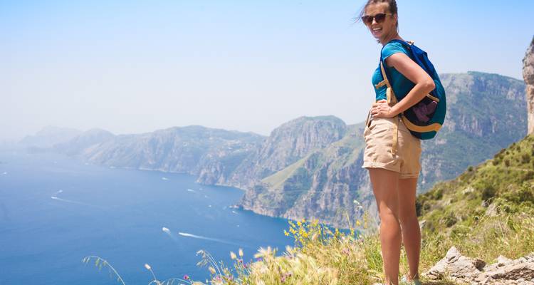 Person standing on a cliff edge overlooking a vast ocean.
