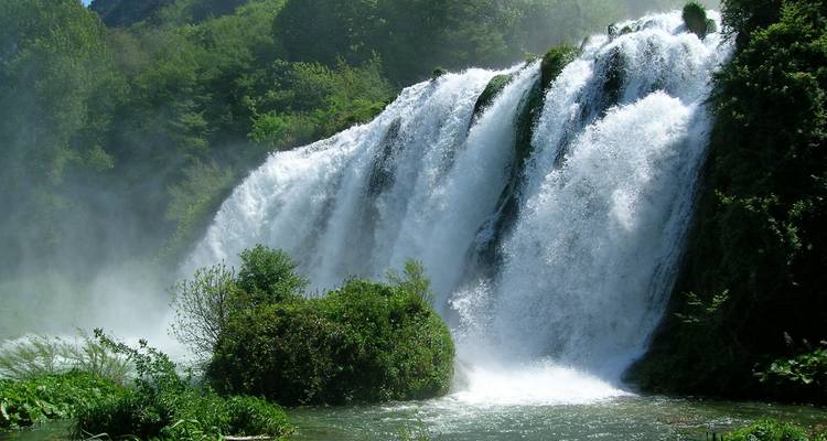 Prächtiger Wasserfall umgeben von üppigem Grün und Nebel.
