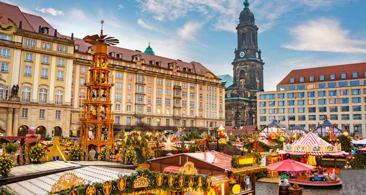 Ein lebhafter Weihnachtsmarkt mit einem zentralen Kirchturm im Hintergrund.