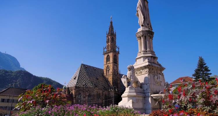 Stadtansicht von Bozen mit Dom und Statue.