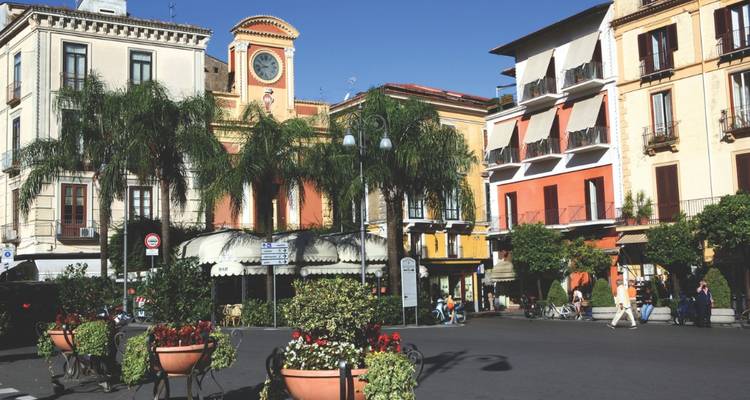 Charmanter mediterraner Stadtplatz in Sorrent mit Palmen, bunten Fassaden and Café-Terrassen.