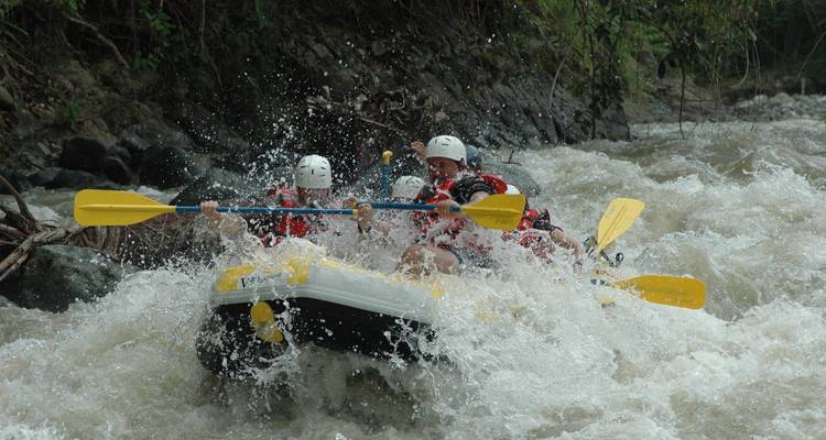Grupo participando en rafting en aguas bravas en un río.