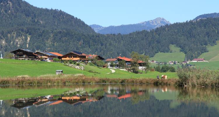 Dorfhäuser im Gebirge mit Bergen und einem See.