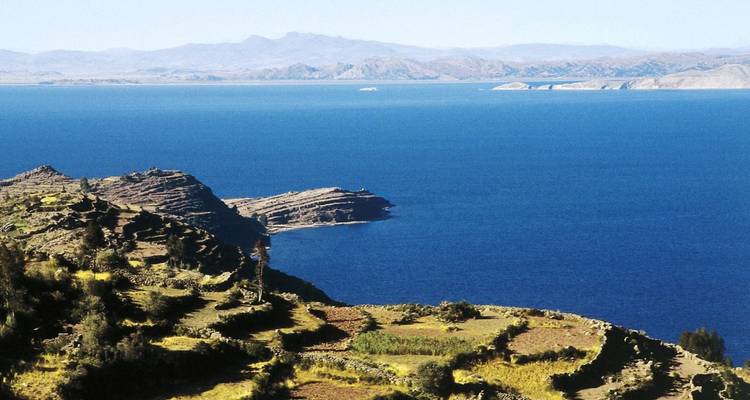 Weitläufiger Blick auf Terrassen und See mit fernen Bergen.