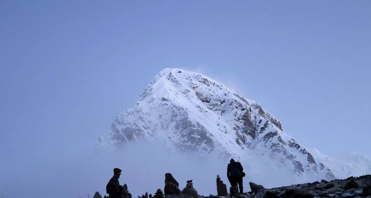 Wandelaar gesilhouetteerd tegen een majestueuze met sneeuw bedekte bergtop.