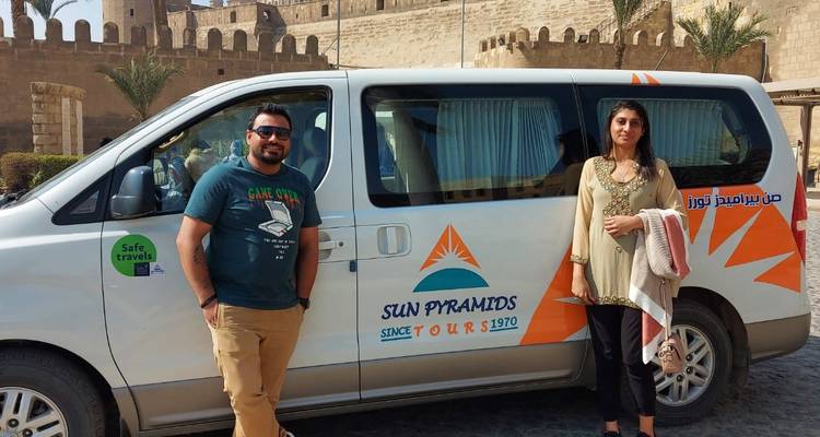 Twee mensen die naast een busje staan met Caïro op de achtergrond.