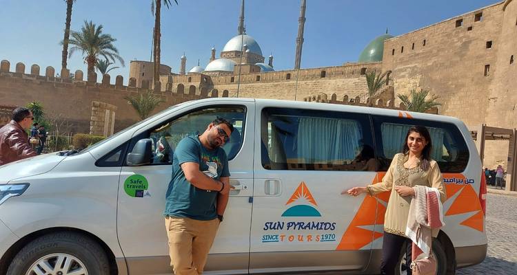 Mensen die poseren met een busje en een moskee op de achtergrond.