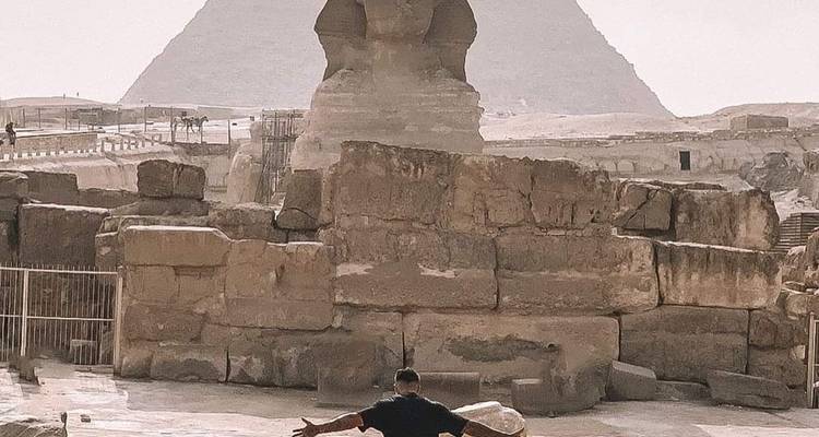 Person with arms outstretched in front of the Sphinx.