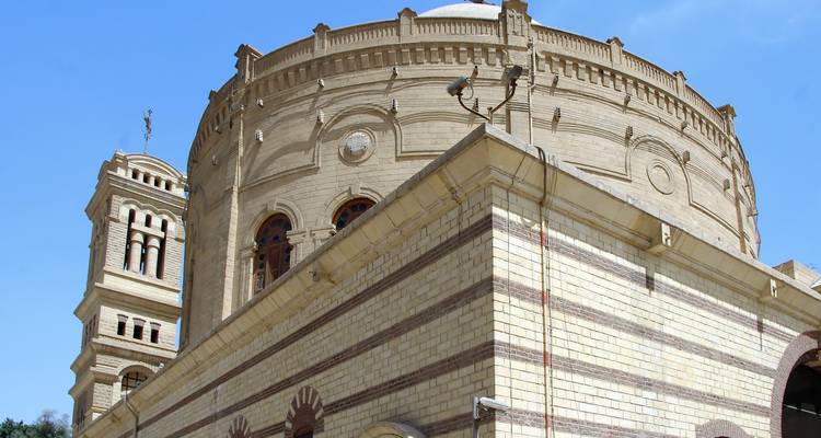 Large domed building with minaret under clear skies.