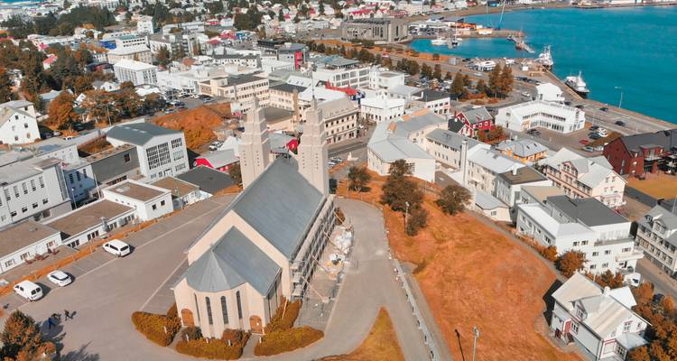 Aerial view of a city with a church and colorful houses by the waterfront.