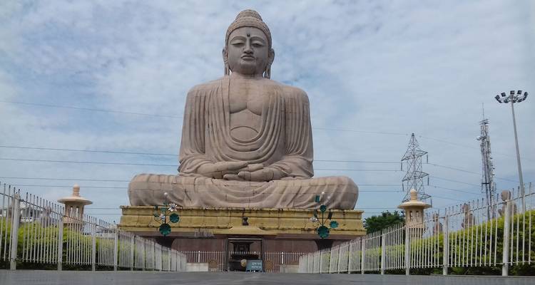 Large Buddha statue at a temple under a cloudy sky.