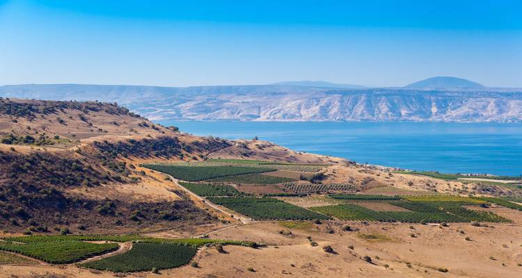 Vasto paisaje con un lago y colinas bajo un cielo azul despejado.