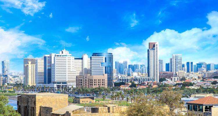 Horizonte urbano moderno con edificios de gran altura bajo un cielo azul brillante.