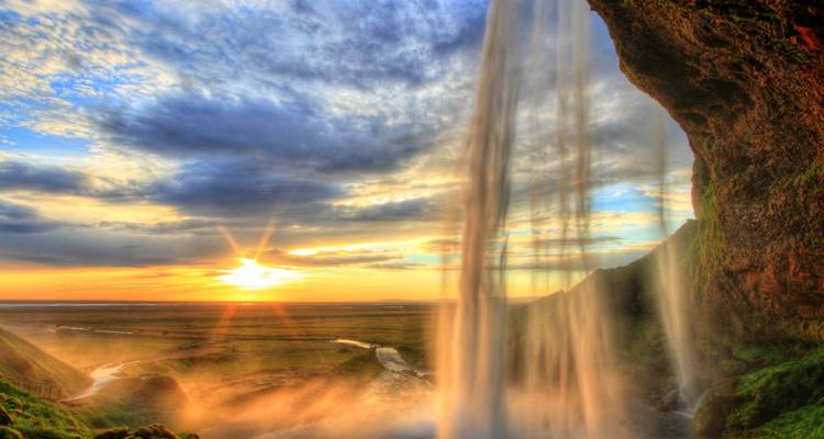 Ein Wasserfall mit der untergehenden Sonne im Hintergrund.
