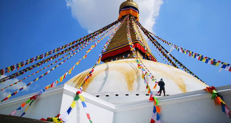 Boudhanath Stupa met kleurrijke gebedsvlaggen en een heldere blauwe hemel.