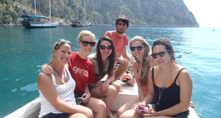 Group of people on a boat with a scenic backdrop of mountains and water.