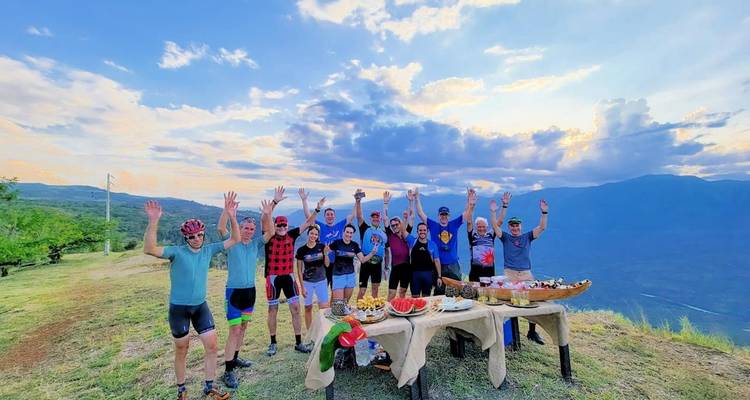Groupe de cyclistes célébrant les mains levées près d'un point de vue panoramique.