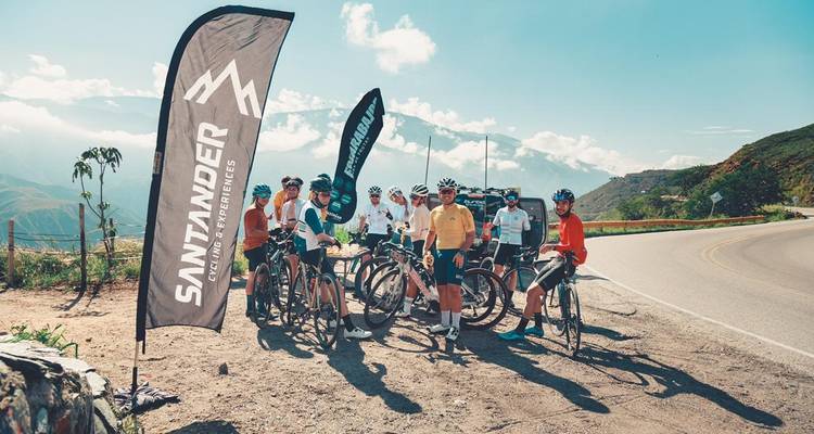 Des cyclistes avec des banderoles sur une route de montagne.