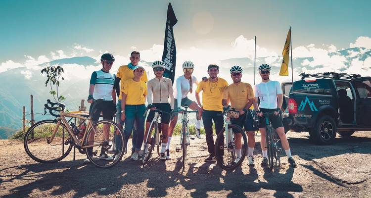 Cyclistes posant avec un véhicule d'assistance sur une route de montagne pittoresque.