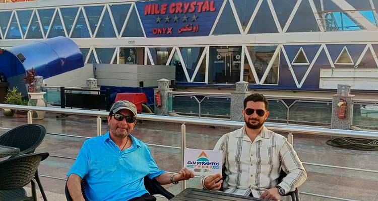 Deux hommes assis devant un navire de croisière amarré à un quai.