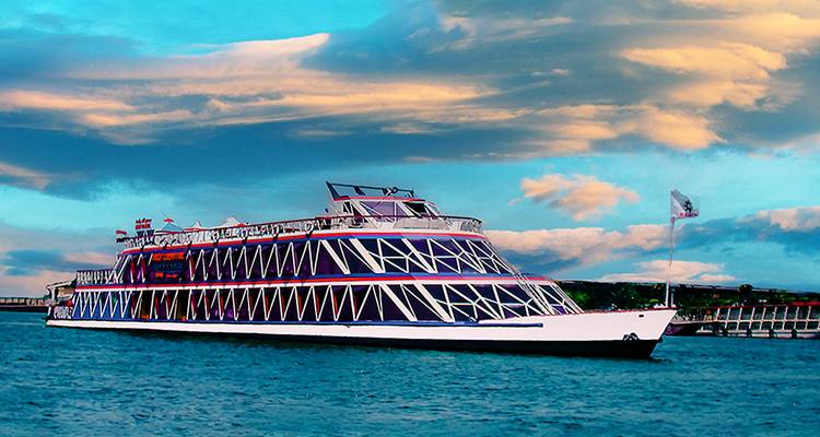 Un navire de croisière naviguant sur une grande étendue d'eau avec des nuages dramatiques au-dessus.